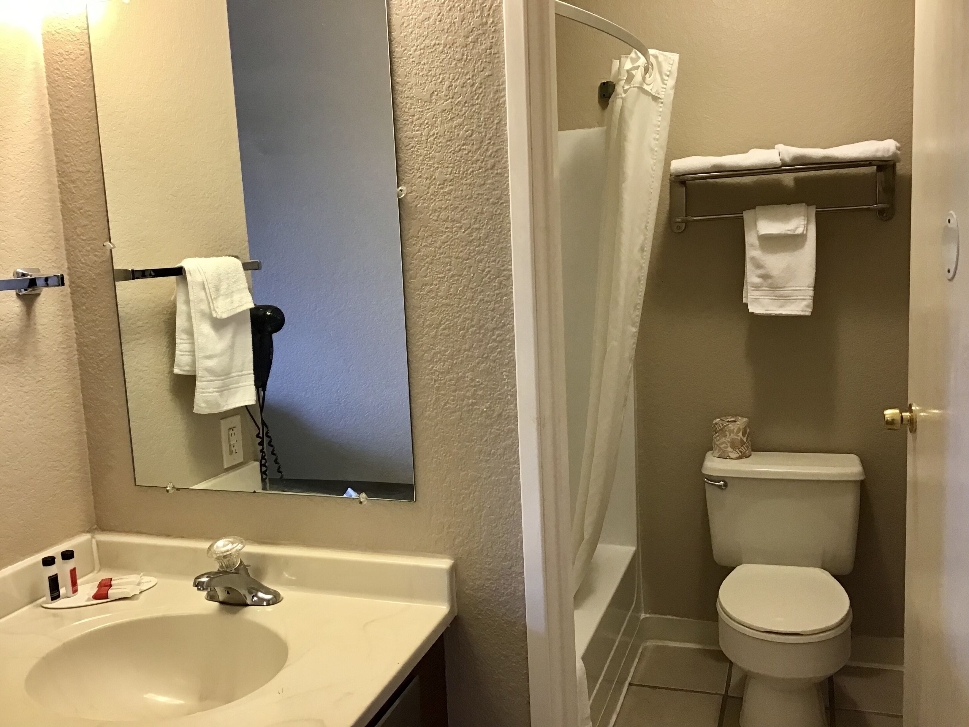 A bathroom with a sink, mirror, toilet, and shower curtain.