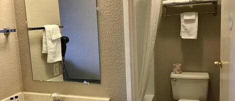 A bathroom with a sink, mirror, toilet, and shower curtain.