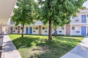 A residential building with multiple doors, some with numbers, and a well-maintained lawn with trees.