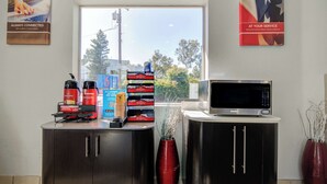 A kitchen with a microwave, a coffee maker, and a coffee station with branded cups. - Motel 6 San Jose, CA - Airport (San Jose)