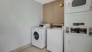 A laundry room with two washing machines and a dryer. - Motel 6 San Jose, CA - Airport (San Jose)