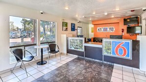 A motel interior with a reception desk, a TV mounted on the wall, and a window offering a view of the street. - Motel 6 Oakland, CA - Embarcadero (Oakland)