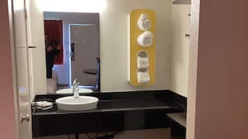 A bathroom with a white sink, black countertop, and a towel rack with towels.