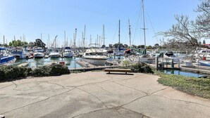 A marina with numerous boats docked, a concrete walkway, and a bench. - Motel 6 Oakland, CA - Embarcadero (Oakland)