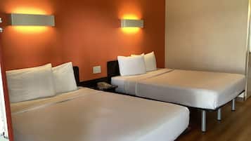 Une chambre d’hôtel avec deux lits simples, une table de chevet avec un téléphone et des lampes fixées au mur.