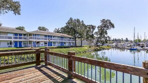 A wooden deck with a railing overlooking a marina with boats and a motel in the background. - Motel 6 Oakland, CA - Embarcadero (Oakland)