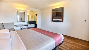 A hotel room with a bed, a desk, a chair, a mirror, and a TV. - Motel 6 Oakland, CA - Embarcadero (Oakland)