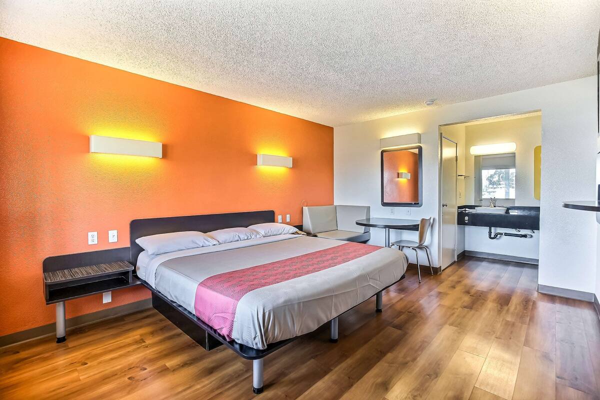 A hotel room with a bed, a desk, and a bathroom.