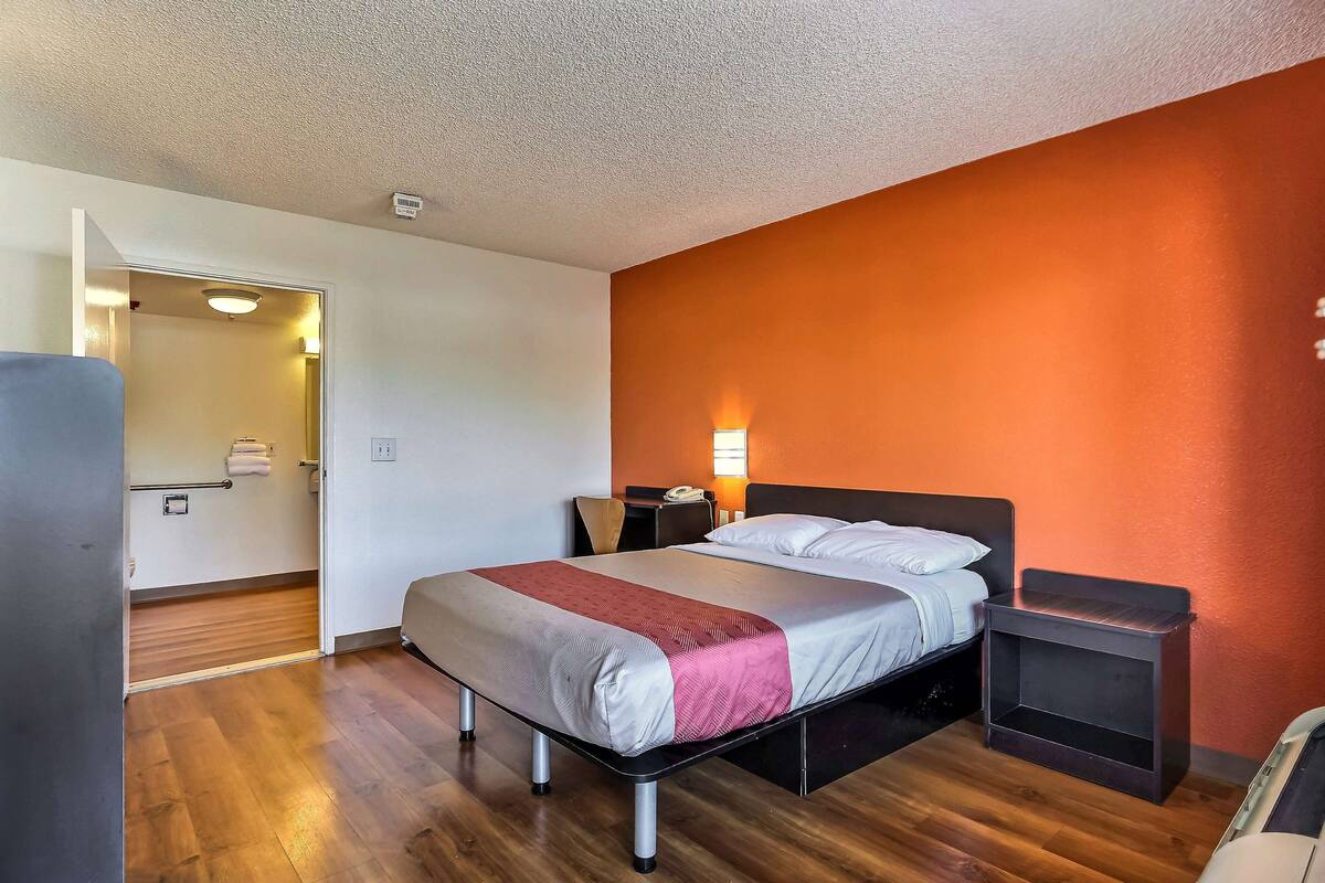 A hotel room with a bed, bedside table, and a nightstand.