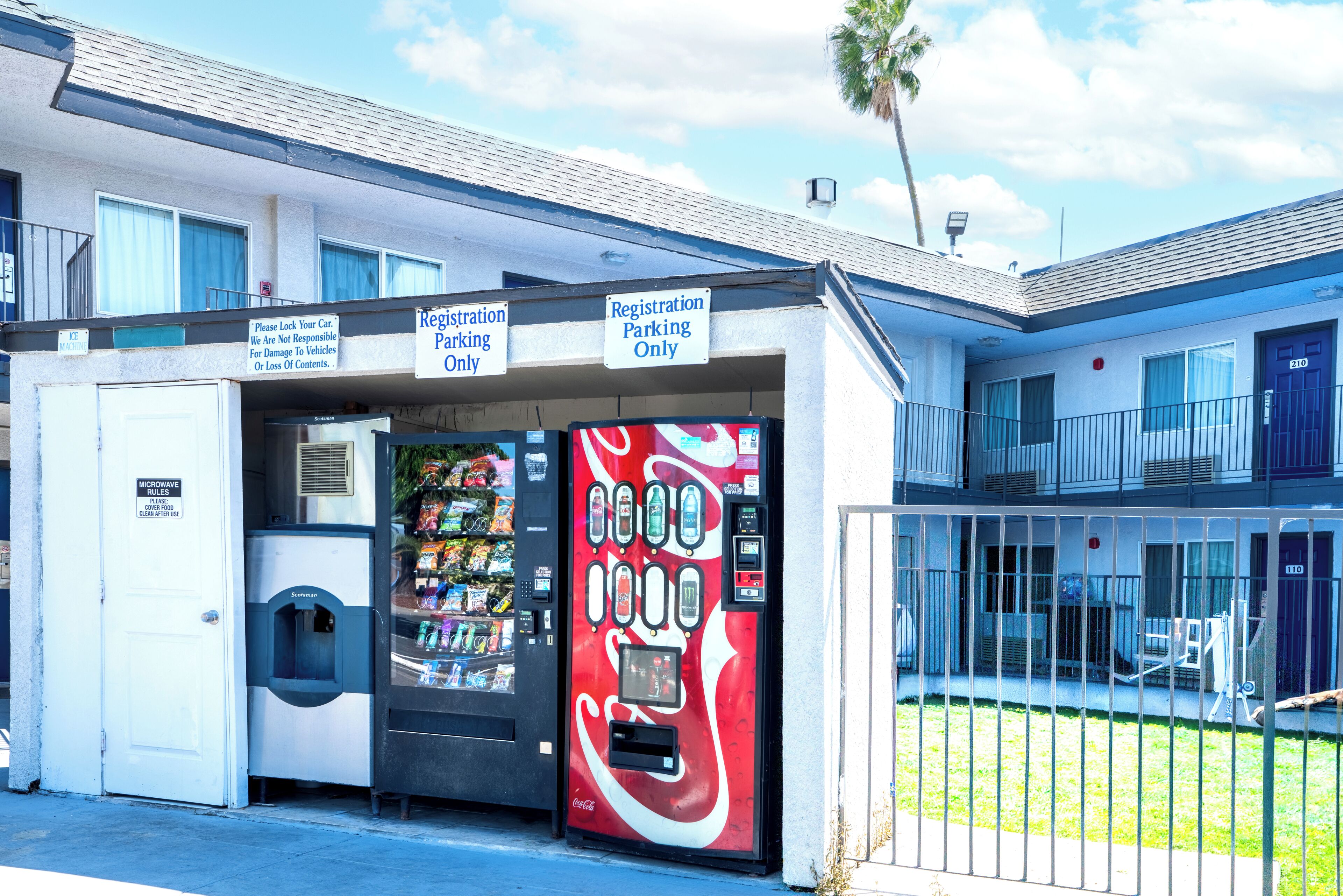 A building with a registration parking sign, a vending machine, and a door with a microwave warning.