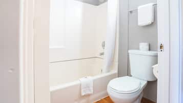 A bathroom with a bathtub, toilet, and shower curtain.