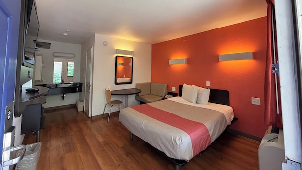 A hotel room with a bed, a desk, a chair, a small table, and a kitchenette. - Super 8 by Wyndham Walnut Creek (Walnut Creek)
