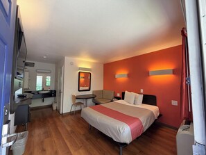 A hotel room with a bed, a desk, a chair, a small table, and a kitchenette. - Super 8 by Wyndham Walnut Creek (Walnut Creek)
