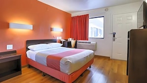 A hotel room with a bed, bedside tables, a window with curtains, an air conditioning unit, and a door. - Super 8 by Wyndham Walnut Creek (Walnut Creek)
