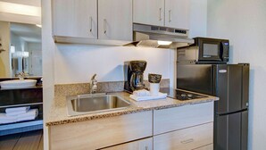 A modern kitchen with a stainless steel sink, a coffee maker, a microwave, and a refrigerator.
