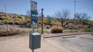 A parking lot with a fenced area, a signboard, and a utility box.