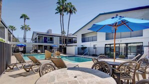 A poolside area with lounge chairs, a table, and umbrellas.