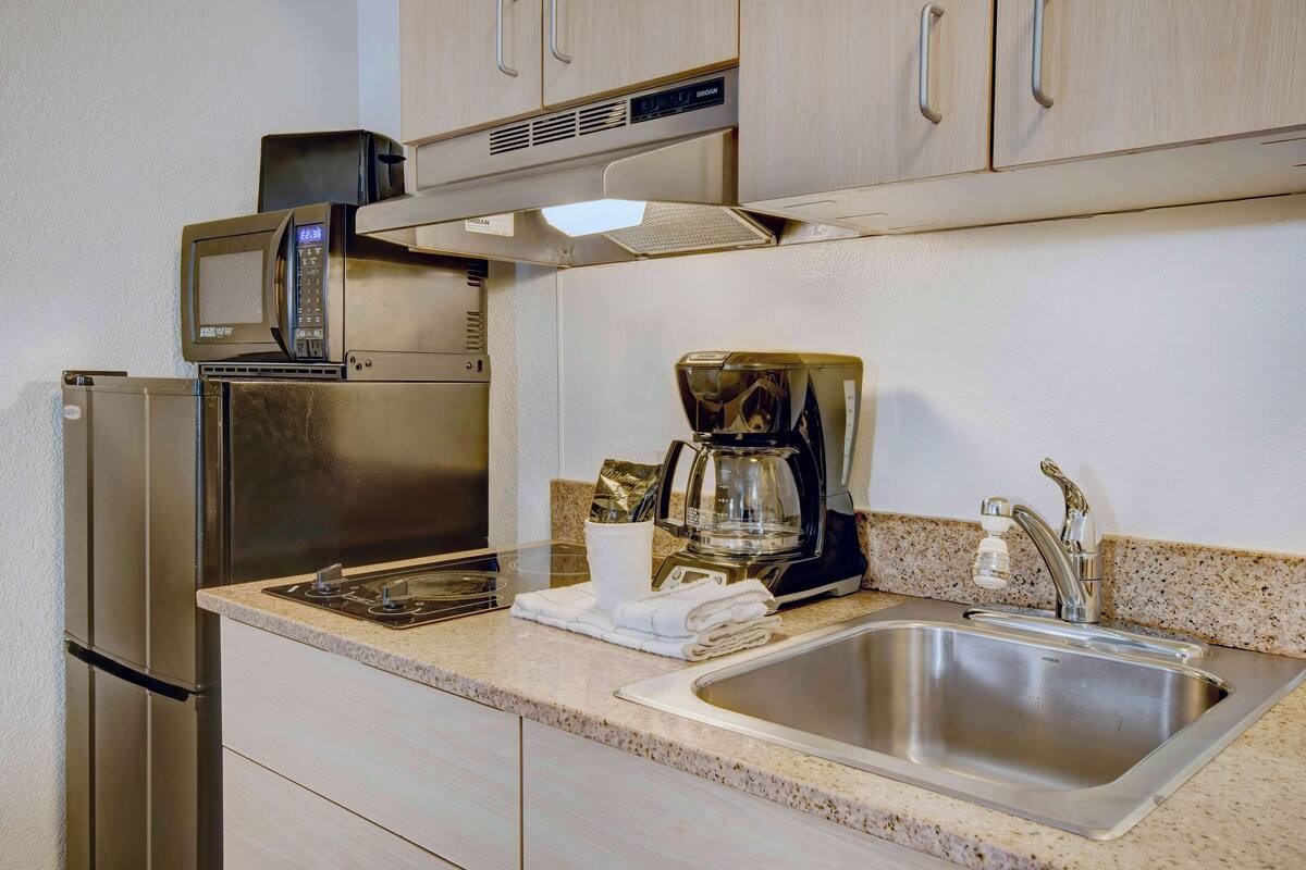 Una cucina moderna con elettrodomestici in acciaio inossidabile, tra cui un forno a microonde, una macchina da caffè e un lavello.