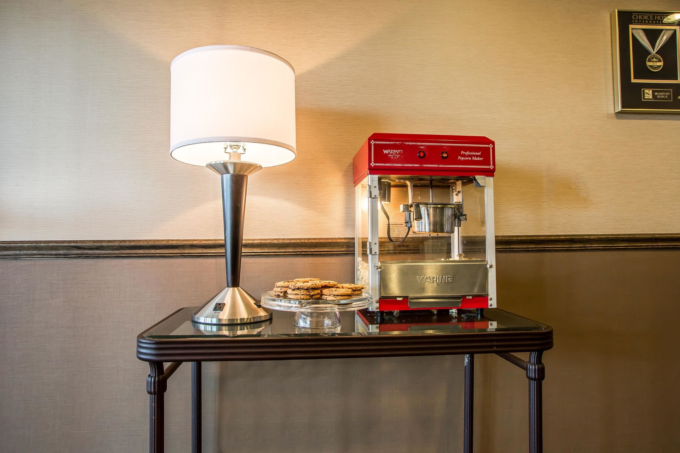 A coffee machine on a table with a lamp and cookies.