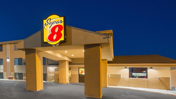 Super 8 -hotelli, jossa on suuri, huomiota herättävä kyltti, massiiviset pylväät ja hyvin valaistu sisäänkäynti.