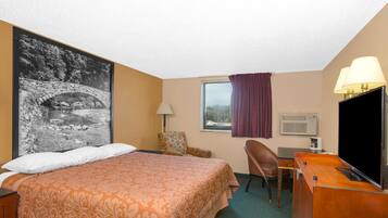A hotel room with a large bed, a desk with a chair, a television, a lamp, and a window with a view of the outdoors.