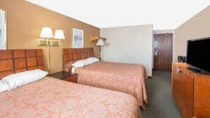 Hotellihuone, jossa on kaksi sänkyä, televisio ja ovi, joka johtaa toiseen huoneeseen.