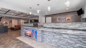 A modern hotel lobby with a reception desk, seating area, and a large sign advertising the hotel.
