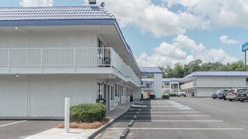 A row of motel buildings with a parking lot in front.