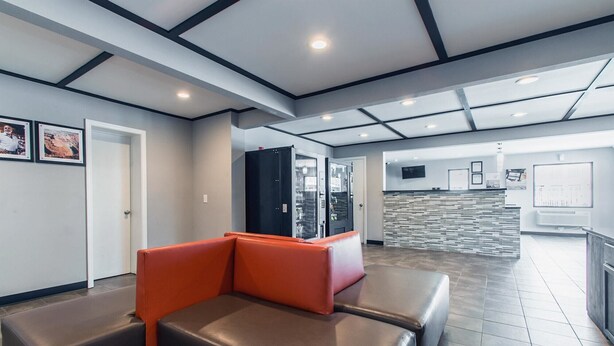 A reception area with a modern design, featuring a reception desk, seating area with cushioned benches, and a wall-mounted TV.