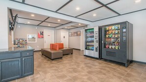 A lobby with a seating area, vending machines, and a reception desk.