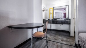 A small, modern bathroom with a sink, mirror, and towel dispenser.