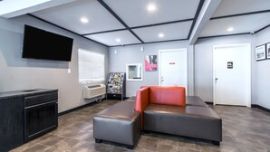 A lobby with a sectional sofa, a flat-screen TV, a magazine rack, and a reception desk.