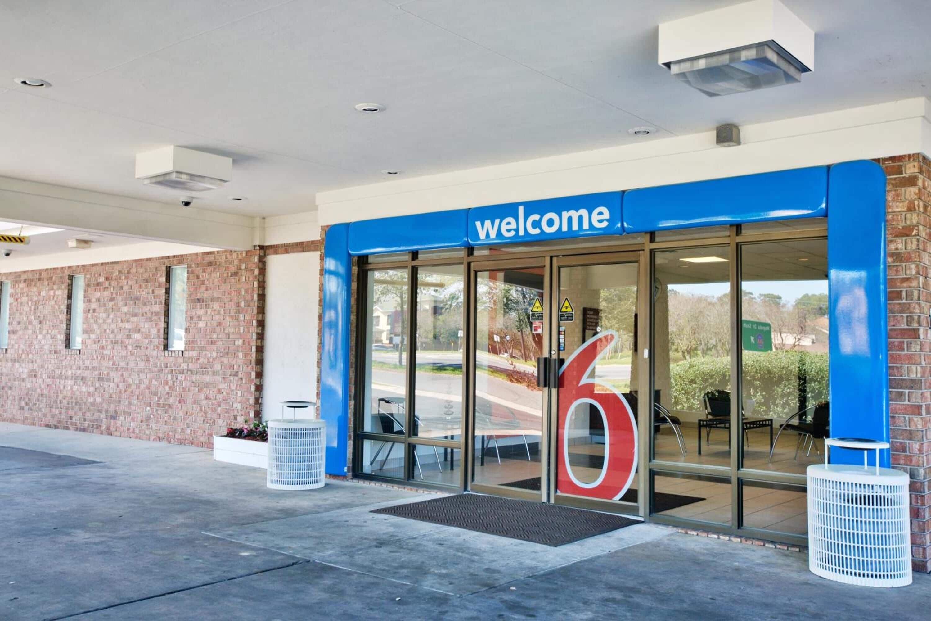 A building entrance with a 'welcome' sign, glass doors, and a large red number '6'.