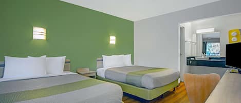 A hotel room with two beds, a desk, a chair, a television, and a bathroom visible through an open door.