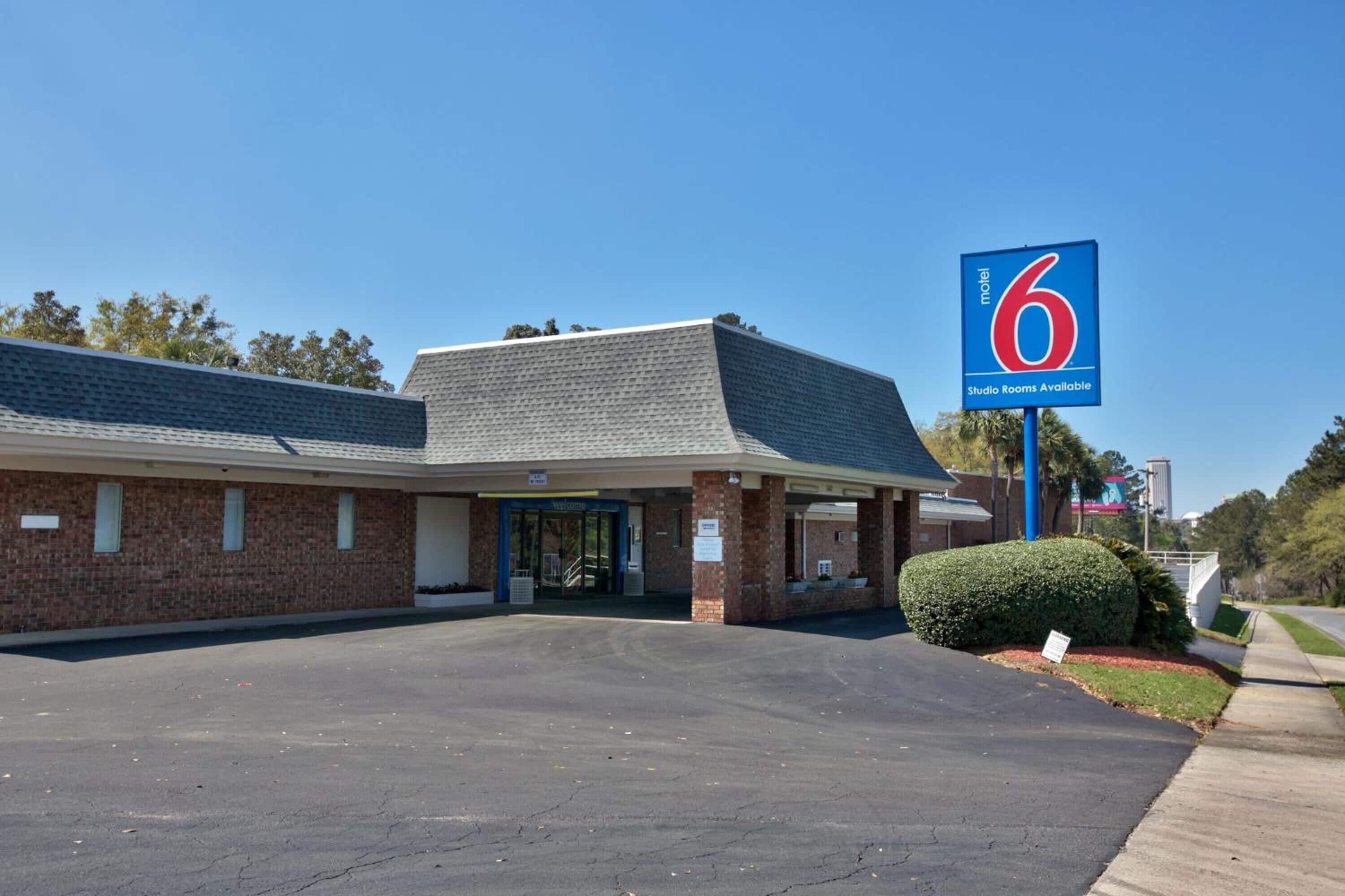 A motel with a blue sign indicating '6 Studio Rooms Available'.