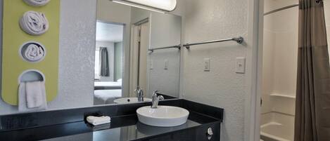 Un baño moderno con lavamanos de encimera negro, un espejo y un perchero con toallas dobladas.