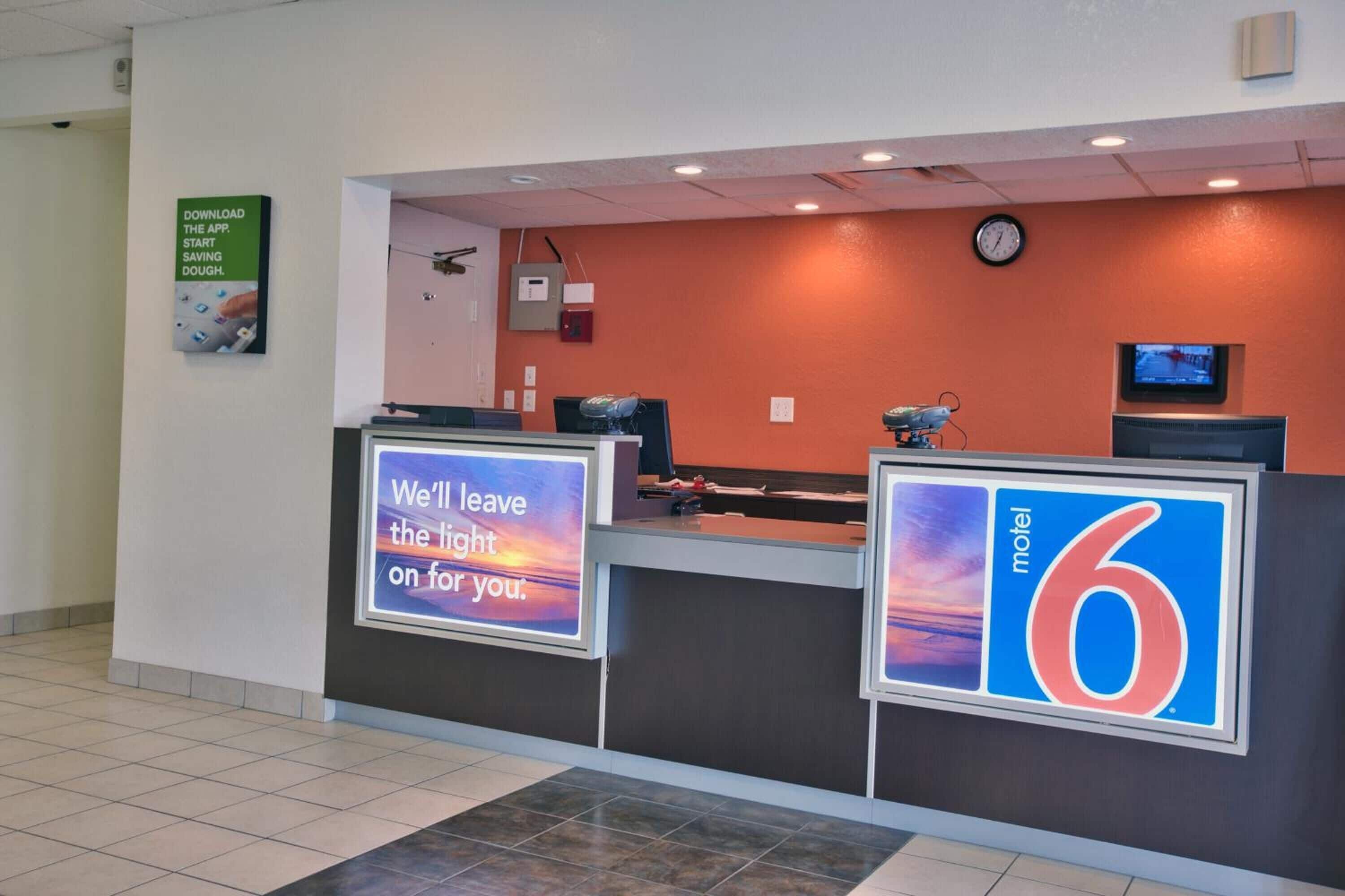 A motel reception desk with a sign that reads "We'll leave the light on for you."