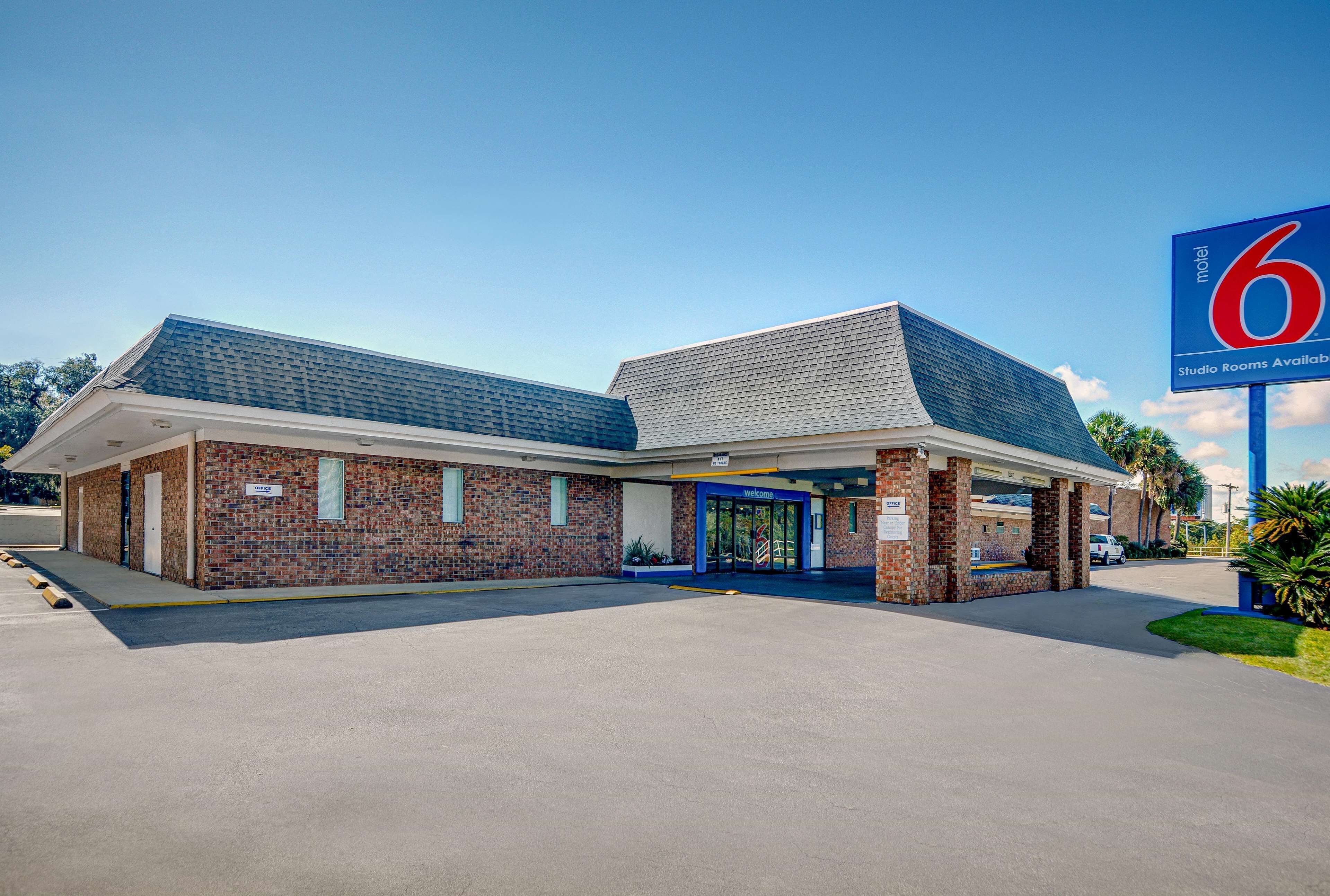 A motel with a brick facade, a blue entrance, and a sign indicating studio rooms are available.