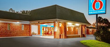 A motel with a brick facade, a blue sign indicating studio rooms, and a welcoming entrance.