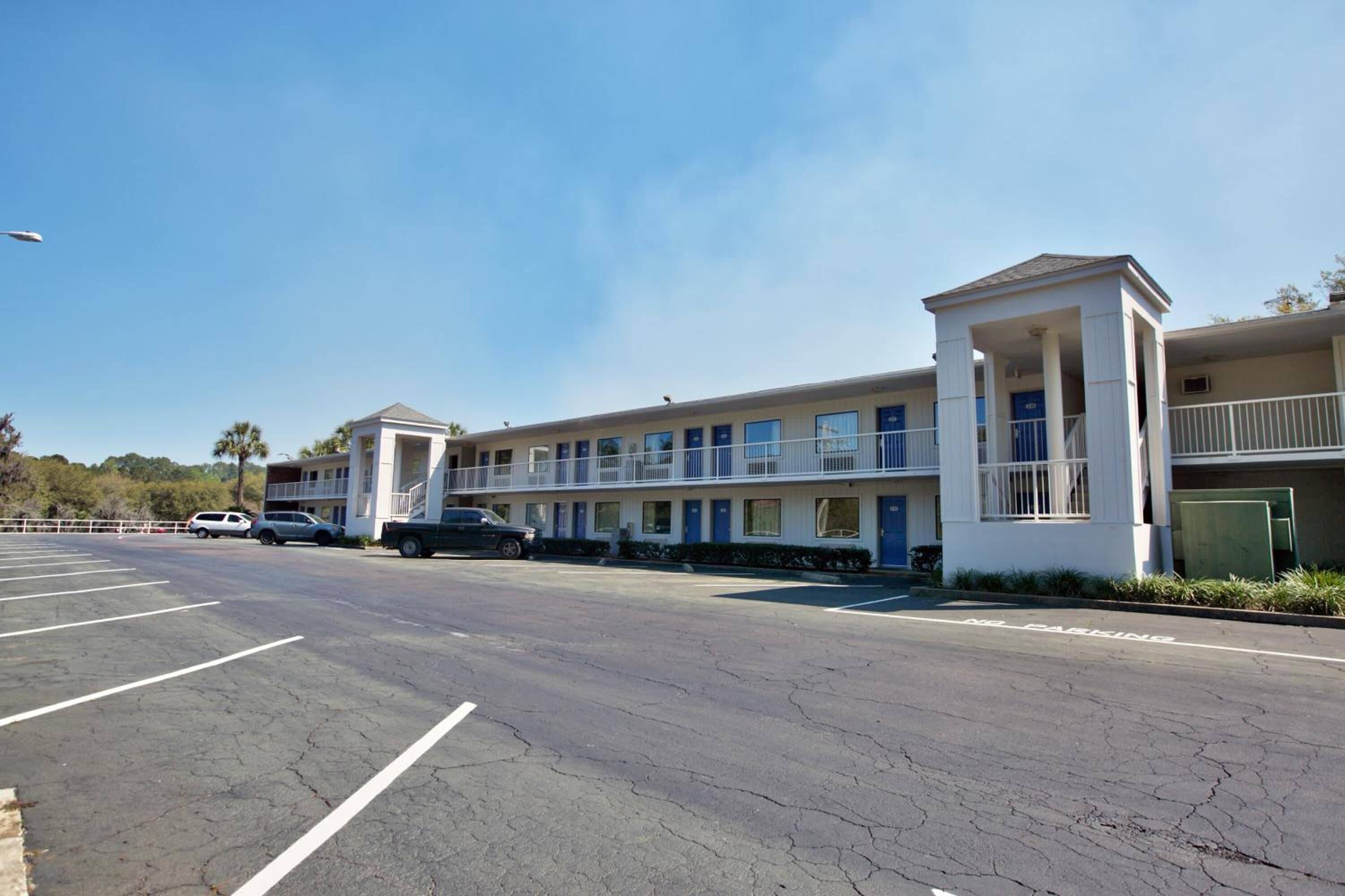 A motel with multiple rooms, a parking lot, and a small structure with columns.