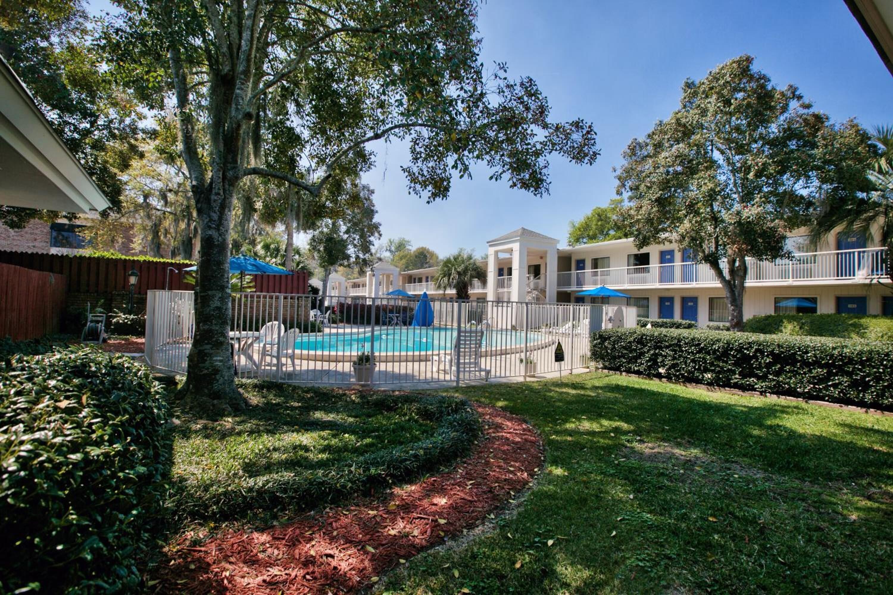 A pool area with a fenced deck, surrounded by well-maintained lawns and trees.