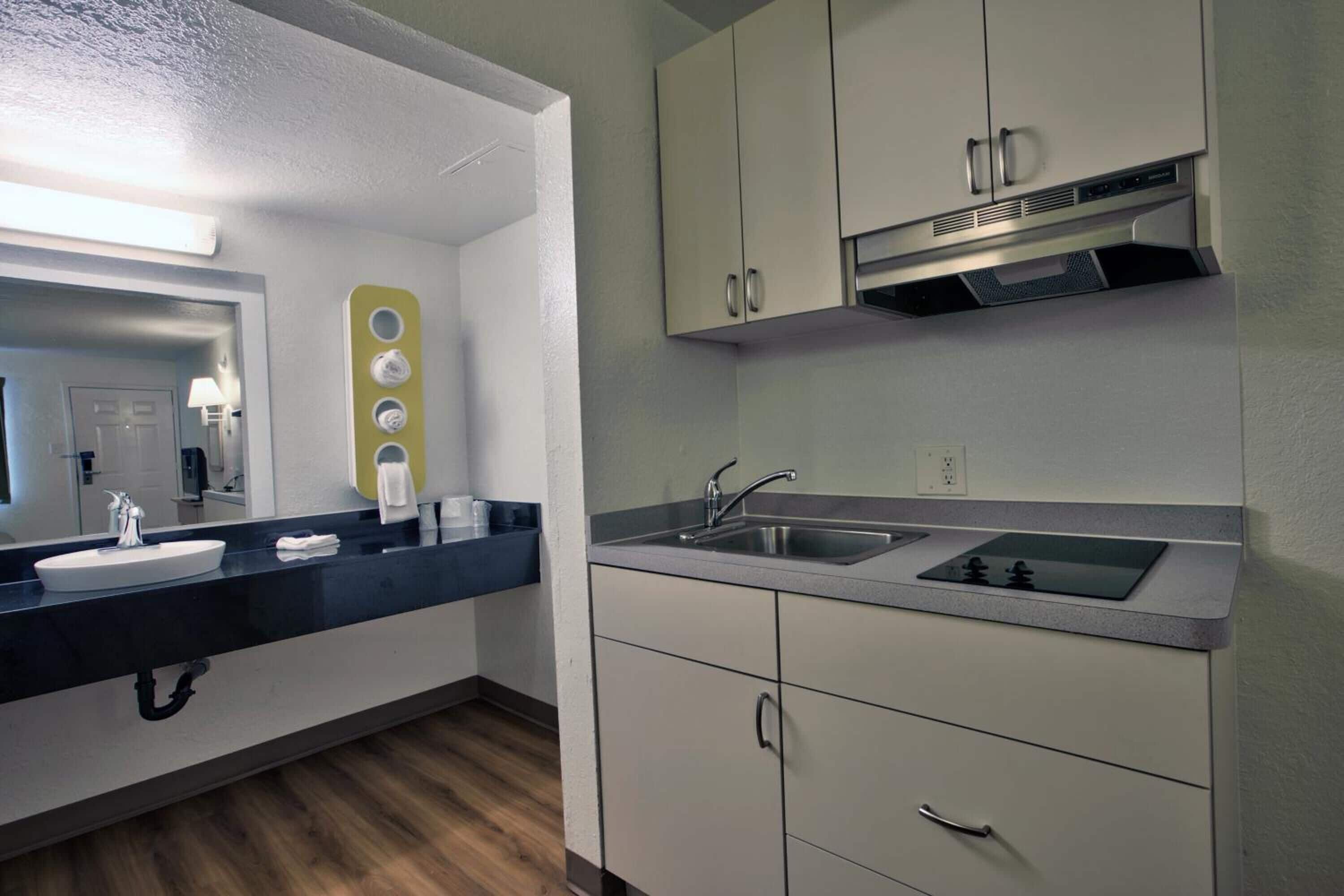A modern kitchen with a black countertop, white cabinets, and a stainless steel sink.