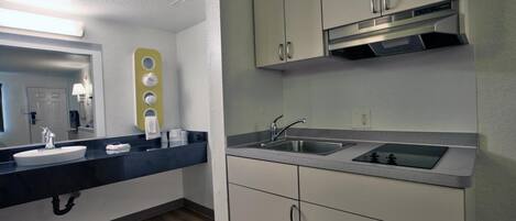 A modern kitchen with a black countertop, white cabinets, and a stainless steel sink.