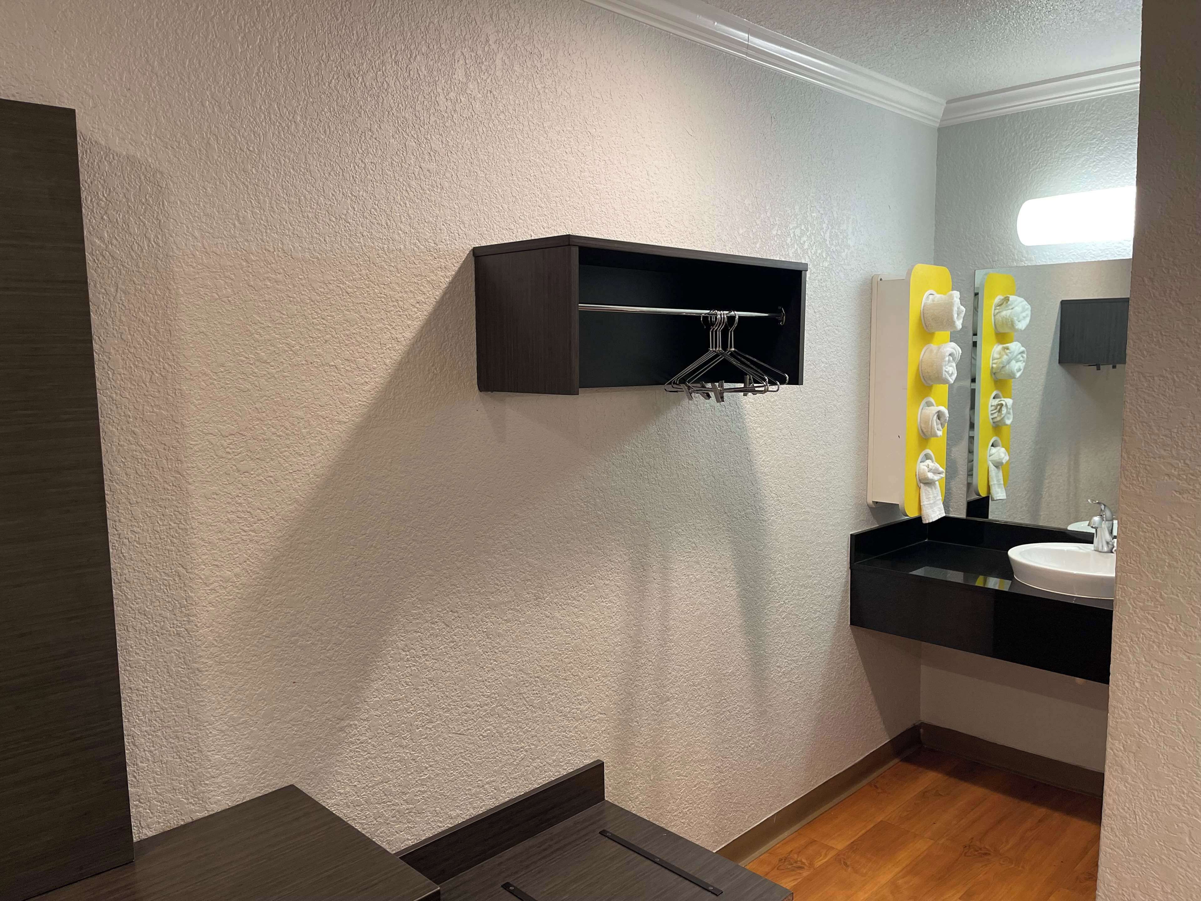 A modern bathroom with a dark wooden vanity, a white sink, and a mirror with towel hooks.