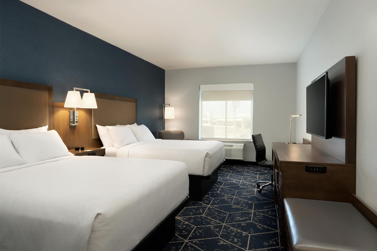 Une chambre d’hôtel avec deux lits, un bureau, une télévision et une fenêtre donnant sur un paysage agréable.