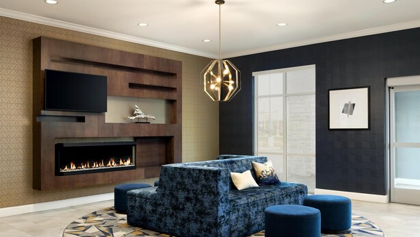 Una sala de estar moderna con chimenea empotrada, un televisor de pantalla plana grande, una lámpara colgante hexagonal única y un tapete estampado.