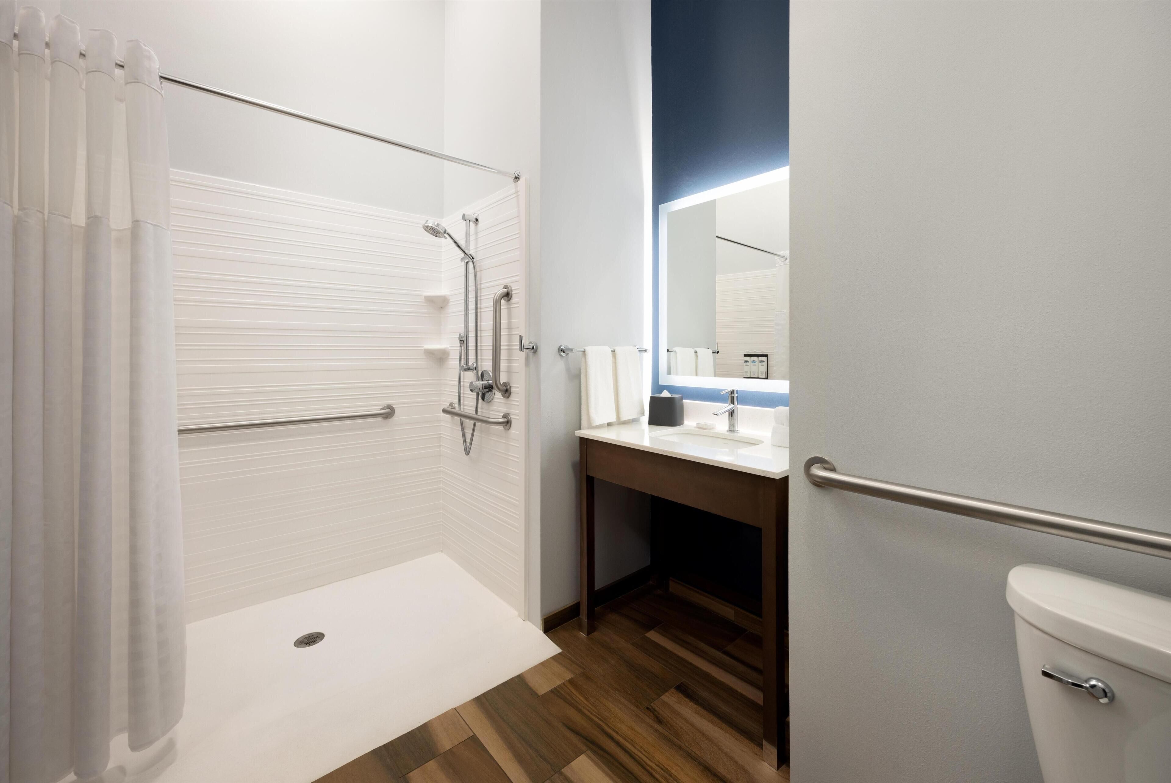 A modern bathroom with a shower, toilet, and sink.