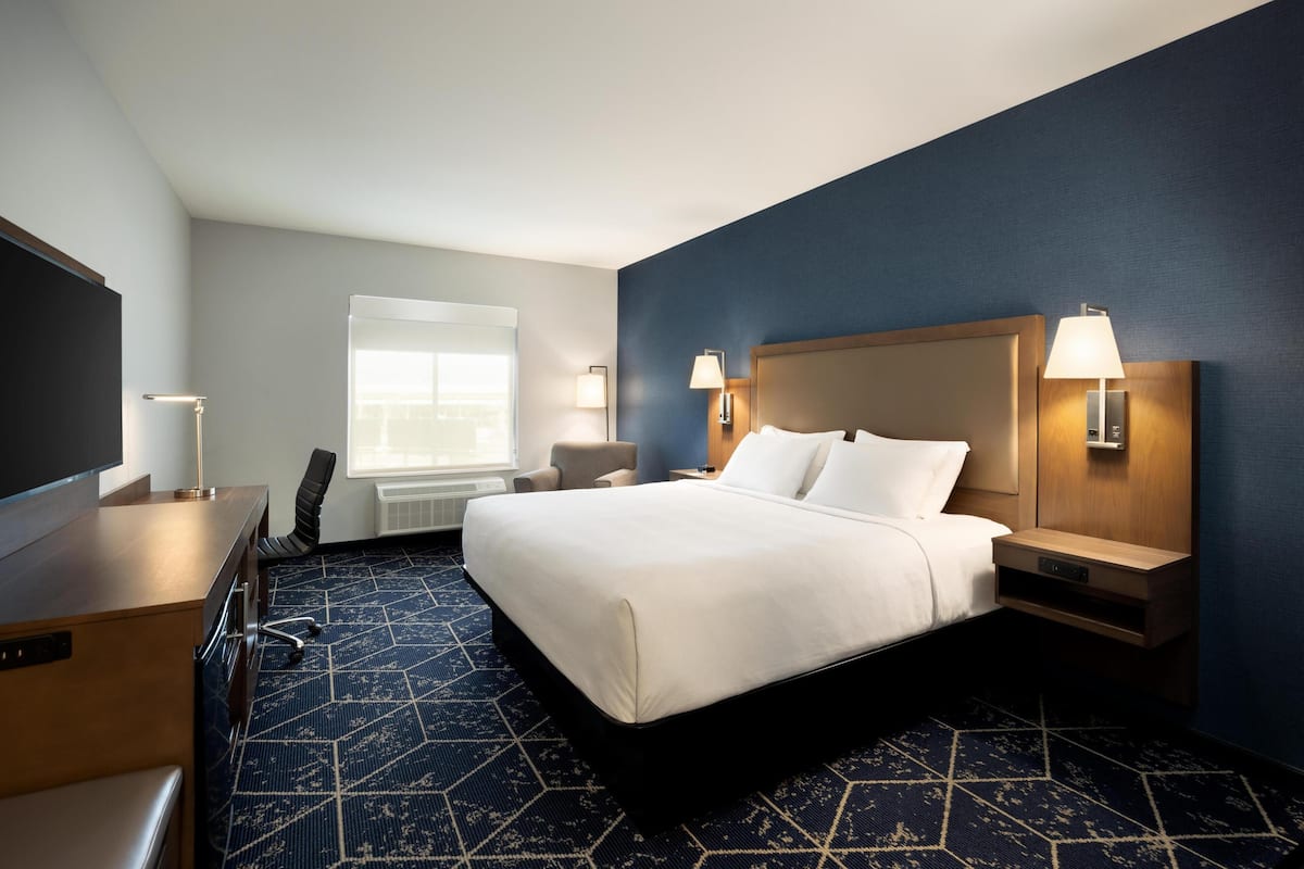 Une chambre d’hôtel comprenant un lit, des tables de chevet, un bureau, une chaise et un téléviseur.