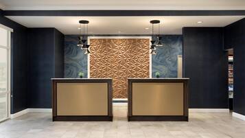 A reception area with two reception desks, a patterned wall, and a tiled floor.
