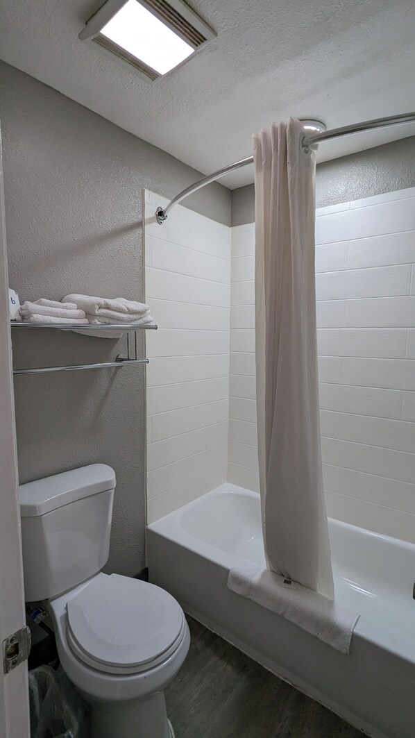 Une salle de bain équipée de toilettes, d’une baignoire et d’un rideau de douche.